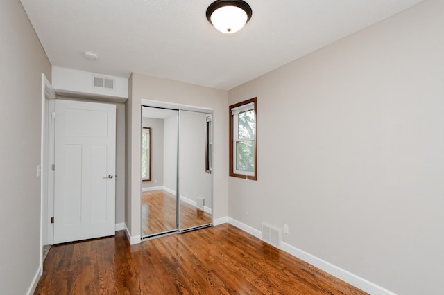 unfurnished bedroom featuring a closet and dark hardwood / wood-style flooring