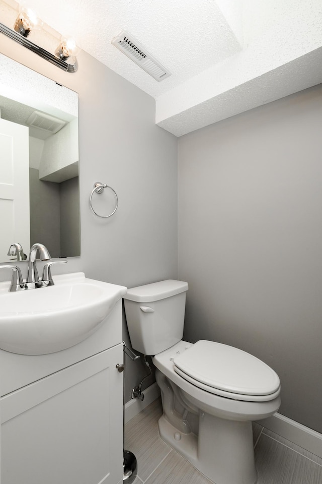 bathroom featuring toilet, a textured ceiling, tile patterned floors, and vanity