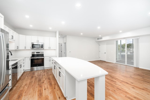 kitchen with sink, white cabinetry, a center island, light hardwood / wood-style flooring, and stainless steel appliances