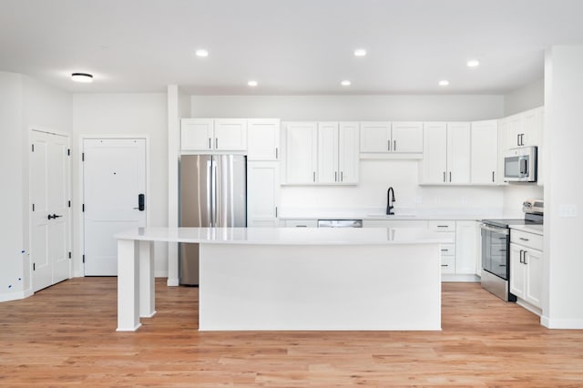 kitchen with white cabinetry, appliances with stainless steel finishes, sink, and a kitchen island