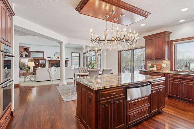 kitchen featuring decorative columns, dark hardwood / wood-style floors, tasteful backsplash, a kitchen island, and decorative light fixtures