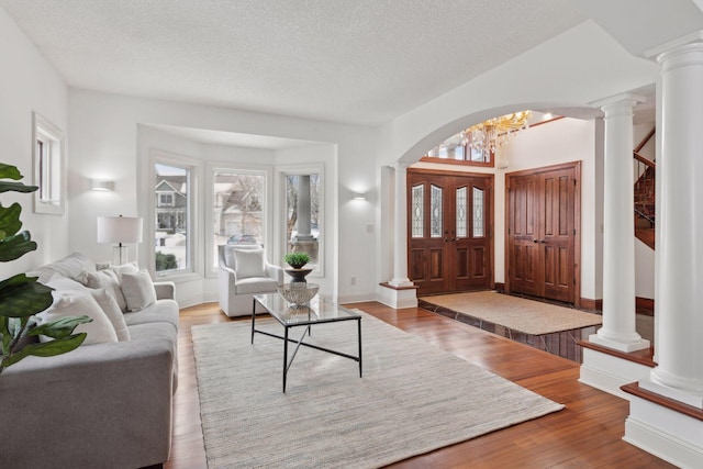 interior space with wood-type flooring, decorative columns, and a textured ceiling