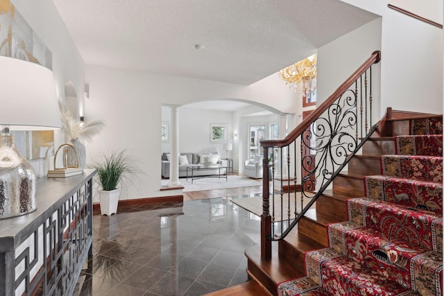 entryway featuring ornate columns and a textured ceiling