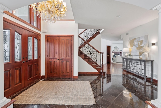 entryway featuring decorative columns, a high ceiling, and an inviting chandelier