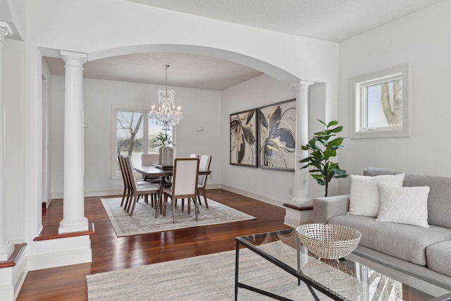 dining room featuring a notable chandelier, decorative columns, and dark hardwood / wood-style floors