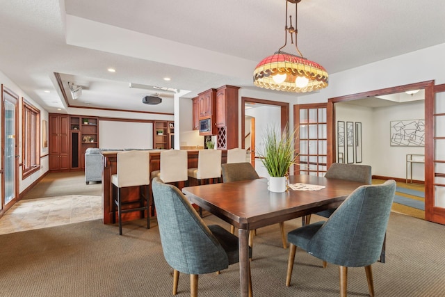 carpeted dining room with a raised ceiling and french doors