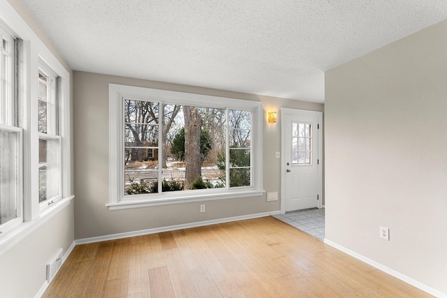 unfurnished room featuring a textured ceiling and light wood-type flooring