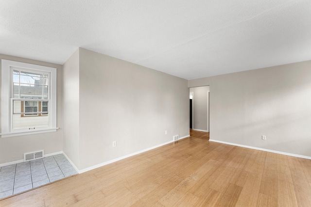 empty room with a textured ceiling and light wood-type flooring