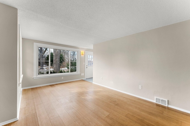 unfurnished room with a textured ceiling and light hardwood / wood-style floors