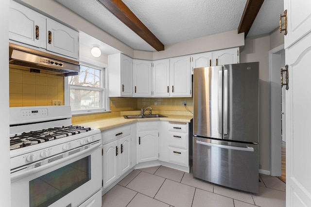 kitchen with white cabinets, sink, white range with gas stovetop, and stainless steel fridge