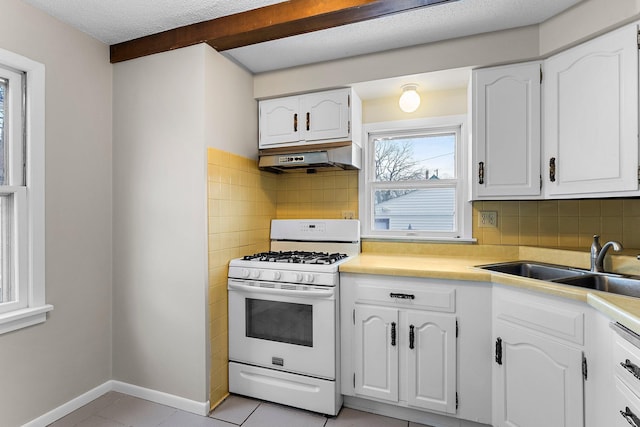 kitchen featuring tasteful backsplash, sink, white cabinets, and white gas range oven