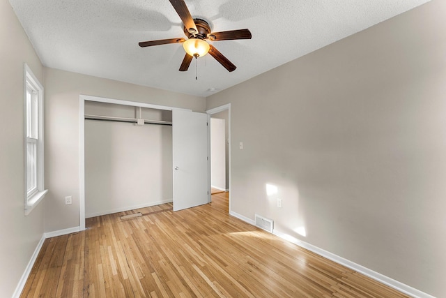 unfurnished bedroom featuring a textured ceiling, a closet, ceiling fan, and light wood-type flooring