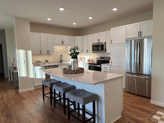 kitchen featuring sink, white cabinets, a kitchen bar, a center island, and stainless steel appliances