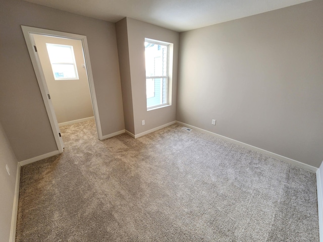 empty room with light colored carpet and a wealth of natural light