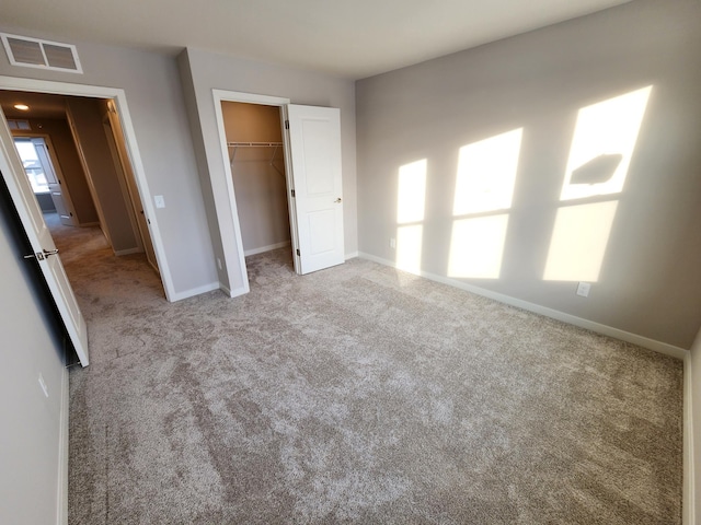 unfurnished bedroom with light carpet, a spacious closet, and a closet