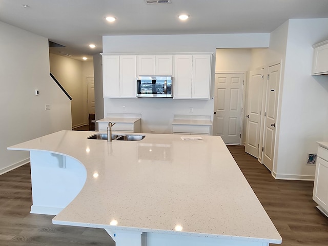 kitchen featuring an island with sink, sink, white cabinets, and dark hardwood / wood-style flooring