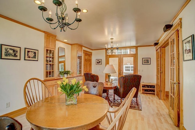 dining room with an inviting chandelier, light wood-style floors, french doors, baseboards, and ornamental molding