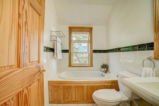 full bath with a garden tub, wainscoting, lofted ceiling, and toilet