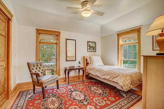 bedroom with baseboards, lofted ceiling, multiple windows, and light wood finished floors