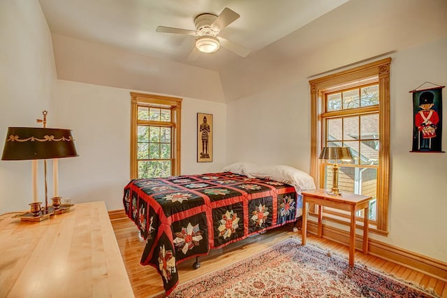 bedroom featuring baseboards, multiple windows, and wood finished floors