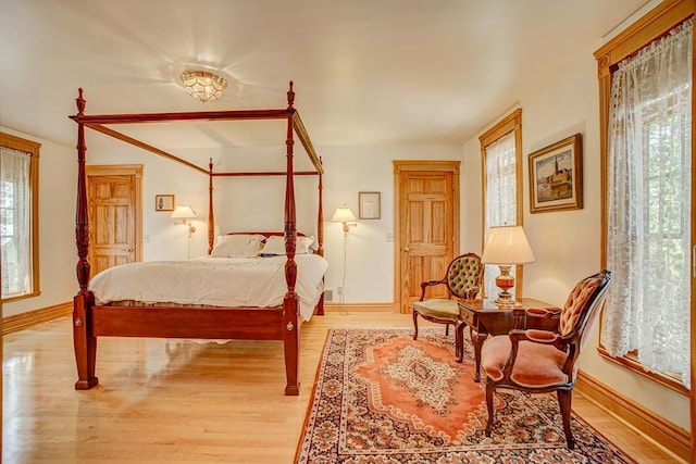 bedroom with baseboards, multiple windows, and light wood finished floors