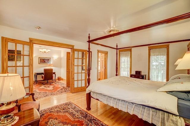 bedroom with french doors, wood finished floors, and a chandelier
