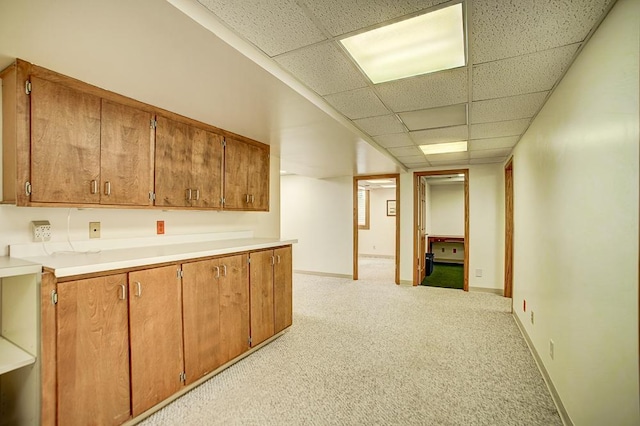 interior space with light colored carpet, baseboards, and a drop ceiling