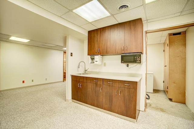 kitchen featuring light countertops, a drop ceiling, black microwave, and light carpet
