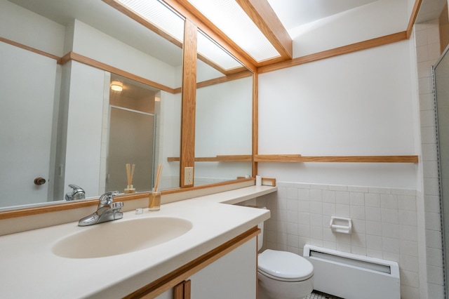 bathroom featuring vanity, toilet, tile walls, and a shower with door