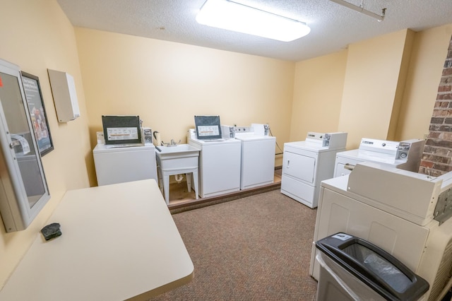 washroom with washer and clothes dryer, light colored carpet, and a textured ceiling