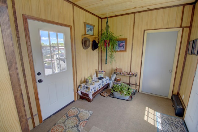 entryway with light carpet, wood ceiling, and wooden walls