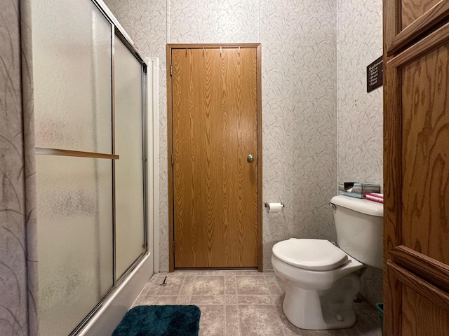 bathroom featuring a shower with shower door and toilet