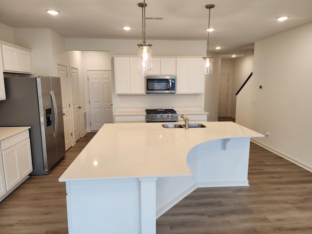 kitchen with pendant lighting, sink, white cabinetry, stainless steel appliances, and a center island with sink