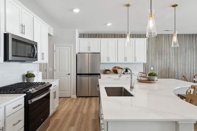 kitchen with stainless steel appliances, sink, a center island with sink, and white cabinets