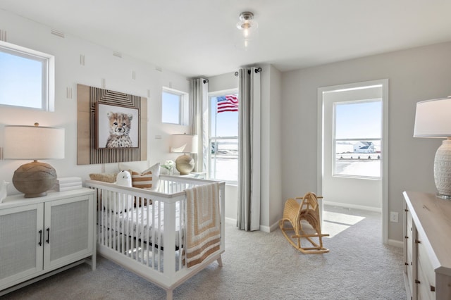 bedroom with multiple windows, a nursery area, and light colored carpet