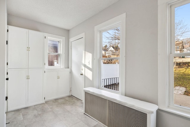 doorway with radiator heating unit and a textured ceiling