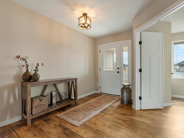 foyer with baseboards, wood finished floors, and a chandelier