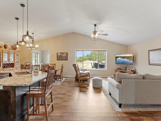 living room featuring wood finished floors, a ceiling fan, vaulted ceiling, and baseboards