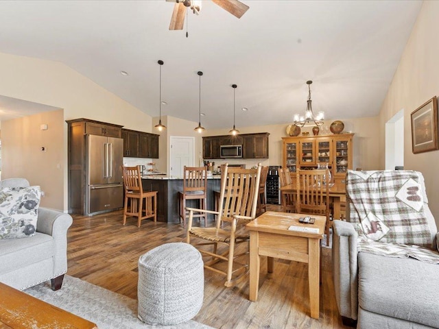 living room featuring vaulted ceiling, light wood-style flooring, ceiling fan, and a chandelier