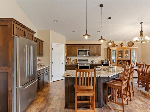 kitchen featuring appliances with stainless steel finishes, a sink, a chandelier, dark wood-style floors, and hanging light fixtures