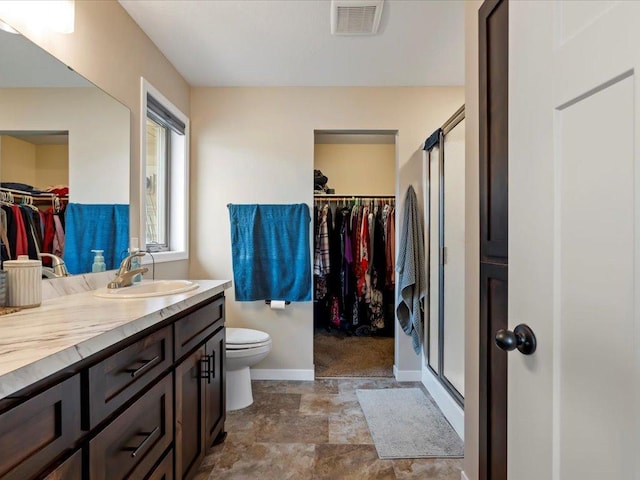 full bath featuring baseboards, a stall shower, vanity, toilet, and a spacious closet