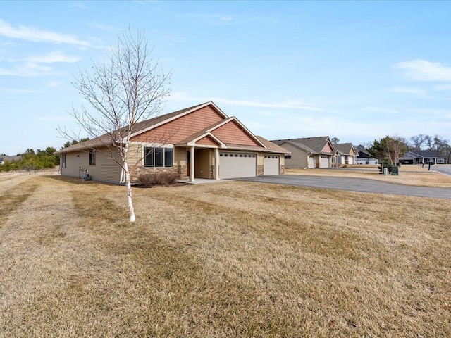view of front of house with an attached garage, asphalt driveway, and a front yard