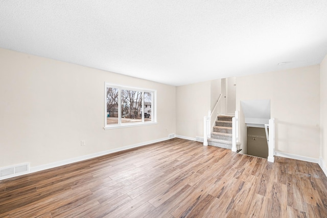 unfurnished living room with hardwood / wood-style flooring and a textured ceiling