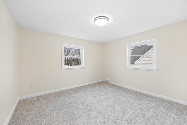 carpeted empty room featuring a textured ceiling