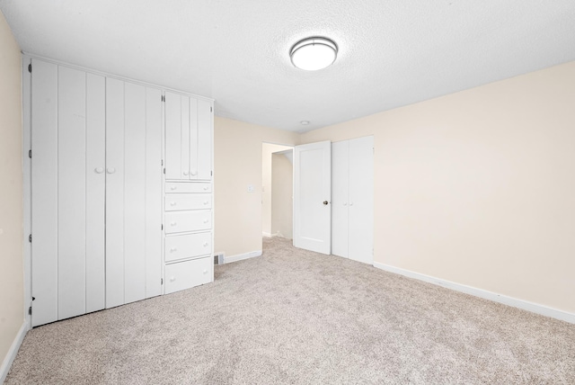 unfurnished bedroom featuring carpet floors, a textured ceiling, and a closet