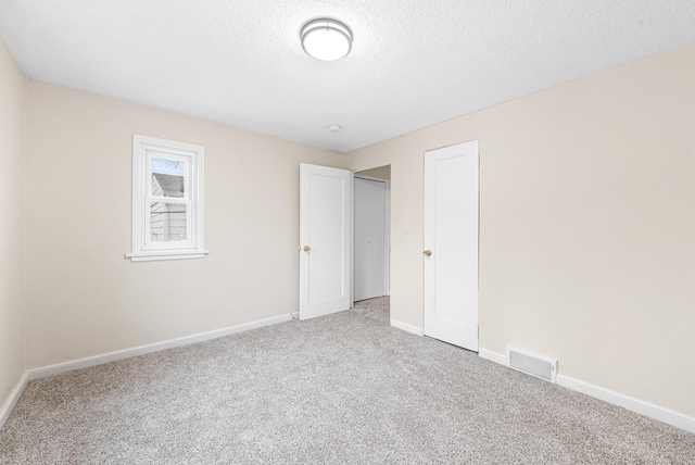 unfurnished bedroom with light carpet and a textured ceiling