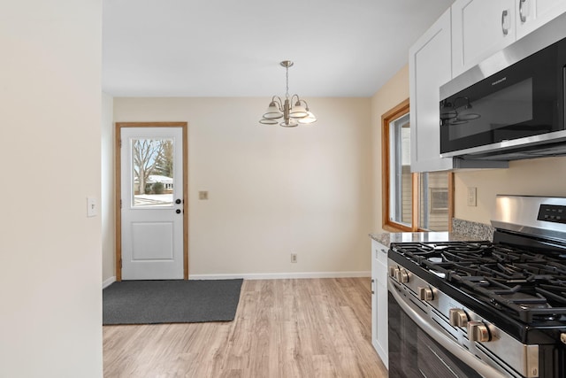 kitchen with white cabinetry, light hardwood / wood-style floors, appliances with stainless steel finishes, hanging light fixtures, and a chandelier