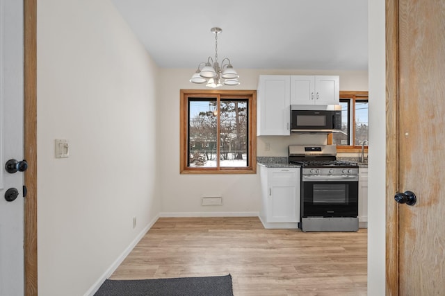 kitchen with stone countertops, pendant lighting, white cabinetry, appliances with stainless steel finishes, and a chandelier