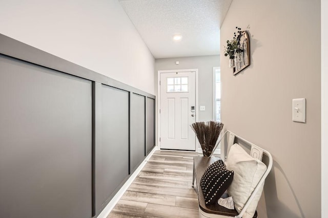 doorway to outside featuring light wood-type flooring and a textured ceiling