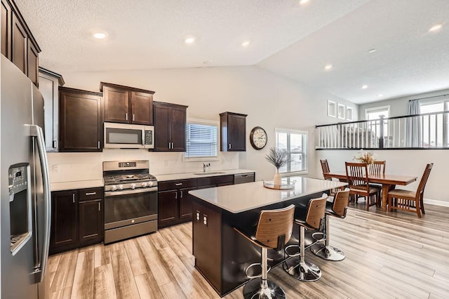 kitchen with appliances with stainless steel finishes, tasteful backsplash, sink, a kitchen island, and light hardwood / wood-style flooring